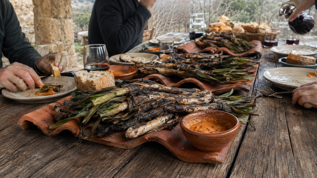Mesa preparada para una calçotada tradicional con calçots, salsa y productos locales.